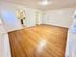 Inviting living room with polished hardwood floors leading to a cozy kitchen, perfect for modern living and entertaining.