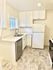 Bright modern kitchen featuring sleek white cabinetry, stainless steel sink, and elegant tiled flooring.