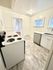 Bright kitchen featuring sleek white cabinetry, modern appliances, and elegant marble-style flooring for a contemporary feel.