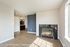 Bright and inviting living room with sleek wooden flooring, featuring a modern fireplace and open-concept kitchen with pendant lighting.