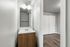 Bright and modern bathroom with sleek sink vanity and a glimpse of the elegant wood flooring in the adjacent room.