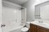 Modern bathroom with sleek white fixtures, spacious bathtub, and elegant wooden cabinetry.