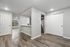 Modern apartment interior showcasing an open kitchen with sleek countertops, natural light pouring in through large windows, and elegant wood flooring.