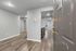 Inviting apartment entrance showcasing sleek hardwood flooring, modern recessed lighting, and an open kitchen layout.
