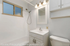 Bright and modern bathroom with elegant vanity, overhead lighting, and a sleek shower area.