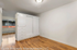 Bright and modern bedroom featuring elegant wood flooring, ample built-in storage, and a large window.