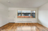 Bright and inviting living space featuring elegant hardwood floors and expansive windows overlooking a modern exterior.