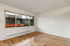Bright apartment room with elegant wooden flooring and a large window offering a charming courtyard view.