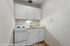 Charming compact kitchen featuring modern white cabinetry, sleek countertops, and cozy lighting.