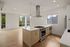 Bright and modern kitchen with sleek stove, island with pendant lighting, and hardwood floors, complemented by large windows offering abundant natural light.
