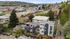 Stunning aerial view of modern apartments surrounded by lush greenery, with a scenic hillside backdrop and vibrant cityscape.