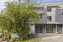 Modern townhouse exterior with sleek design, featuring large windows, greenery, and vibrant mural accents.