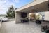 Spacious covered rooftop patio with modern tiles, offering scenic city and tree views, ideal for outdoor relaxation.