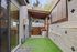 Charming outdoor patio with artificial grass and built-in BBQ grill, ideal for entertaining.
