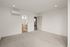 Spacious empty room with plush carpets, featuring a sleek air conditioning unit and access to a well-lit modern bathroom.
