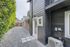 Charming exterior view of a modern home with sleek black siding and brick accents, featuring a clean gravel driveway and lush landscaping.