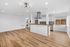 Modern open-concept kitchen and living area featuring sleek wooden floors, elegant lighting fixtures, and stainless steel appliances.