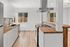 Modern kitchen with sleek white cabinetry, elegant wood countertops, and abundant natural light from large windows.