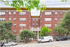 Charming red brick apartment building with lush greenery and classic architectural details, offering a welcoming and stylish urban living experience.