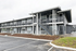Modern two-story apartment building with sleek black railings and convenient parking, offering an inviting and accessible living space.