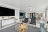 Bright and modern living area featuring chic furnishings, a large wall-mounted TV, and expansive windows offering natural light.