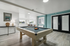 Modern lounge area with a sleek pool table, stylish decor, and abundant natural light through large windows.
