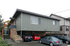 Modern two-story apartment building with stylish green exterior, featuring covered parking and lush landscaping.