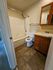 Inviting bathroom featuring elegant tiled flooring, contemporary bathtub, and stylish wooden vanity with bright lighting.