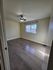 Inviting bedroom with sleek hardwood floors, abundant natural light from a large window and an elegant ceiling fan.
