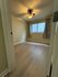 Inviting bedroom with chic wood flooring, large window, and modern ceiling fan creating a warm and airy ambiance.