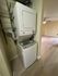Convenient in-unit stacked washer and dryer with adjacent open living space featuring modern flooring and a ceiling fan.