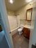 Cozy bathroom with elegant tiled flooring, chic vanity, and a modern shower-tub combo.