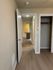 Inviting apartment hallway with warm wooden floors leading to a cozy kitchen with pendant lighting.