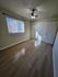 Bright and welcoming bedroom featuring sleek wooden flooring, a modern ceiling fan, and ample closet space with sliding doors.