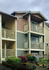 Charming two-story apartment building with stylish balconies, nestled in a lush garden setting, perfect for serene living.