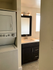 Contemporary apartment bathroom featuring sleek vanity, illuminated mirror, and convenient in-unit laundry.