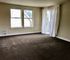 Bright and spacious living room with large windows and elegant sheer curtains, offering abundant natural light.