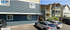 Charming apartment complex with modern blue and beige exterior, ample parking, and inviting balconies.