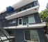 Charming three-story apartment building with modern railings, featuring a large balcony and a vibrant blue exterior, perfect for stylish urban living.