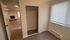 Contemporary apartment featuring a cozy room with a sliding closet, large window, and view into a spacious living area with a fireplace.