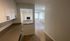 Bright and inviting open-concept kitchen leading to a spacious living area with a cozy fireplace and large windows, perfect for modern living.