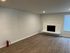 Modern living room featuring sleek hardwood floors, a stylish white stone fireplace, and ample natural light.