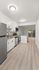 Modern kitchen with sleek white cabinetry, stainless steel appliances, and a spacious open layout leading to a bright living area with floor-to-ceiling windows.