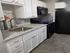 Elegant kitchen featuring sleek granite countertops, modern appliances, and stylish white cabinetry with a fresh backsplash.