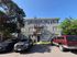 Charming three-story brick apartment building with a classic metal fire escape, shaded by tall trees and featuring convenient parking space.