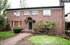 Charming brick apartment building with classic architecture, surrounded by lush greenery and a well-maintained pathway.