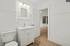 Sleek bathroom with elegant vanity and modern lighting, opening to bright living space with stylish wood flooring.