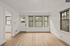 Bright and airy living space with elegant wood flooring and large windows opening to greenery.