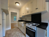 Charming kitchen with modern appliances, ample cabinet storage, and stylish countertops, adjacent to a bright living room with hardwood flooring.