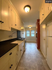 Charming galley kitchen with vintage cabinetry, modern lighting, and ample natural light from large windows.